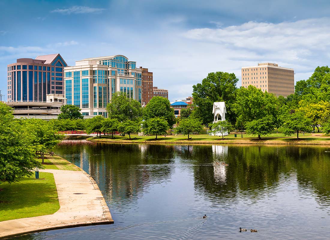 Contact - Scenic View of Commercial Buildings in Downtown Huntsville Alabama Next to a Park with Green Trees and a River